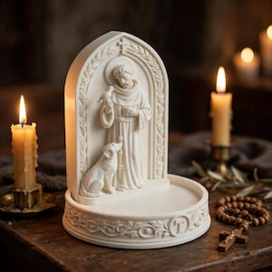 May include: An off-white resin sculpture featuring a figure in robes standing under an arched frame with a bird and a dog. The base is circular with decorative relief carvings and a letter T. The sculpture has a smooth, matte finish throughout.