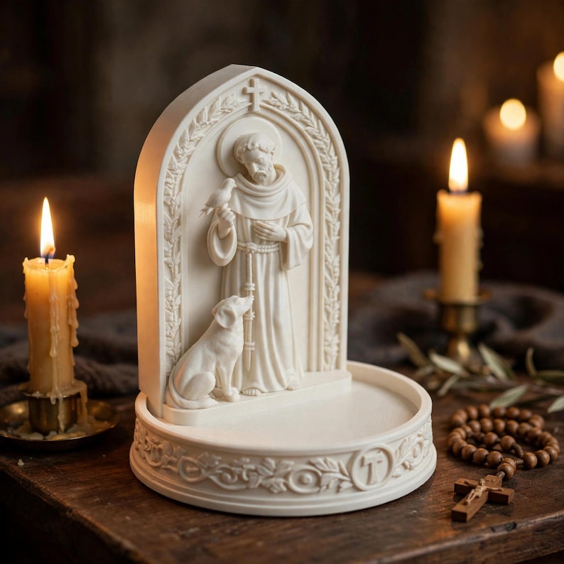 May include: An off-white resin sculpture featuring a figure in robes standing under an arched frame with a bird and a dog. The base is circular with decorative relief carvings and a letter T. The sculpture has a smooth, matte finish throughout.