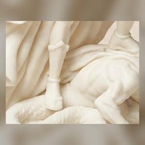 May include: A cream-colored sculpture depicting a figure wearing a greave and sandal, standing over a recumbent form with textured, scale-like details. The composition features flowing, draped fabric elements and smooth, carved anatomical surfaces.