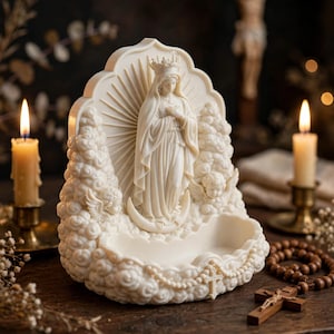 May include: A cream-colored religious figurine featuring a central figure wearing a crown and robes, standing on a crescent moon. The sculpture is surrounded by clouds and cherubs, with a small basin at the base and a cross detail on the front.