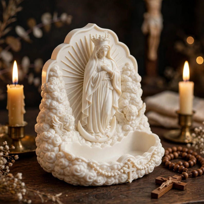 May include: A cream-colored religious figurine featuring a central figure wearing a crown and robes, standing on a crescent moon. The sculpture is surrounded by clouds and cherubs, with a small basin at the base and a cross detail on the front.
