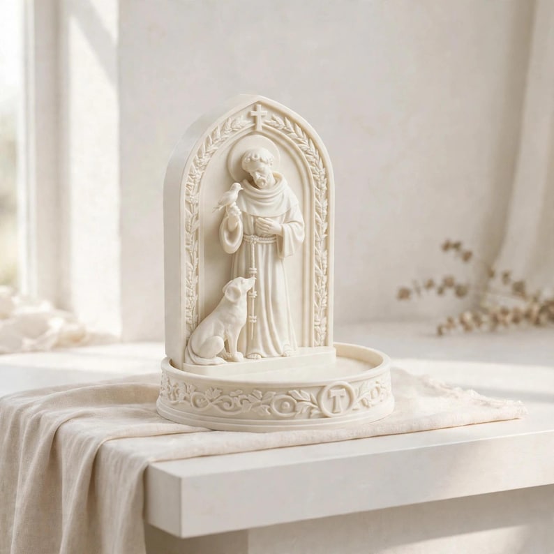 May include: An off-white, arched sculpture featuring a robed figure standing with a bird perched on one hand and a dog sitting at their feet. The base is circular with a decorative border and a central letter T, all rendered in a matte finish.