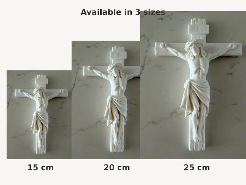 May include: Three white wall crucifixes featuring a sculpted figure of Jesus on the cross. The text "Available in 3 sizes" appears above, with "15 cm", "20 cm", and "25 cm" labels below each respective cross, indicating the available height options.