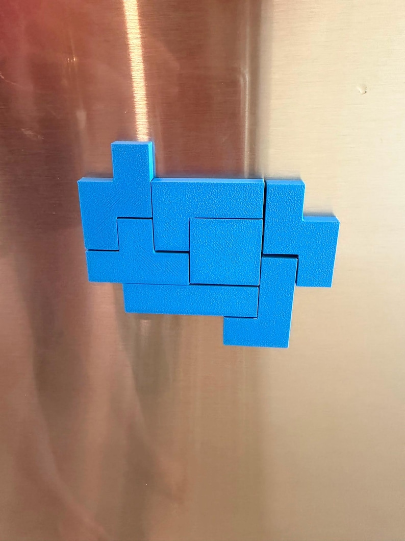 Op de afbeelding: Een set felblauwe geometrische kunststof blokken gerangschikt in een cluster. De stukken hebben een getextureerd oppervlak en zijn gevormd als verschillende in elkaar grijpende puzzelcomponenten, die lijken op klassieke videospelblokvormen.