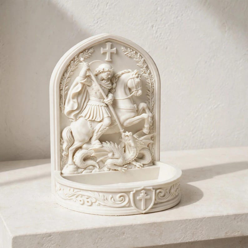 K&ouml;nnte beinhalten: Ein cremefarbener, bogenf&ouml;rmiger Weihwasserbecken-Wandbehang mit einem Relief von Sankt Georg zu Pferd, der einen Drachen mit einer Lanze besiegt. Der Sockel enth&auml;lt ein kleines Becken und ein Schildemblem mit einem Kreuz, alles in matter Optik.