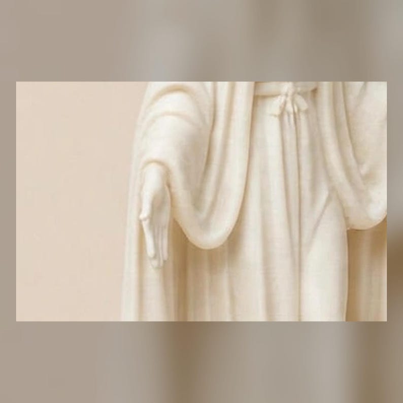 May include: A cream-colored statue depicting a figure draped in flowing, textured robes. The sculpture features a visible hand extended forward with fingers slightly parted, and the fabric of the garment shows intricate folds and a tied waist.