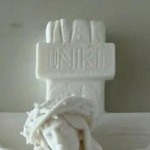 May include: A white matte sculpture of a crucifix featuring a figure wearing a crown of thorns. The top section of the cross displays the embossed text INRI. The entire object is rendered in a solid, uniform white finish with detailed carvings.