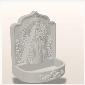 Puede incluir: Una pila de agua bendita blanca para pared con una escultura en relieve de una figura coronada con halo, que viste una t&uacute;nica larga con patrones florales intrincados y sostiene un rosario. La base es un cuenco semicircular con volutas.