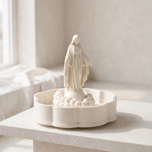 May include: A cream-colored figurine of a standing figure wearing a hooded robe with arms outstretched, positioned atop a small globe surrounded by sculpted clouds, all resting inside a shallow, scalloped-edge circular tray.