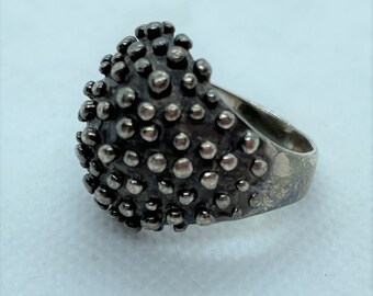 Large silver ring with round spikes.