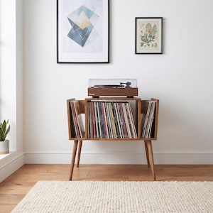 May include: A wooden record player console with tapered legs, featuring a central storage compartment filled with vinyl records and side storage sections. A dark brown turntable with a clear dust cover sits on the top surface of the console.