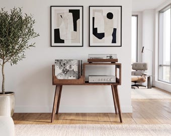 Könnte beinhalten: Ein Plattenspieler-Konsolentisch aus dunklem Holz mit vier konisch zulaufenden Beinen, der links ein vertikales Fach für Schallplatten und rechts ein horizontales Regal mit einem silbernen Verstärker sowie einem Plattenspieler oben bietet.