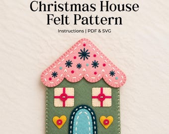 May include: A digital download for a Christmas House Felt Pattern including PDF and SVG instructions. The felt house features a scalloped pink roof with dark blue star embroidery, a sage green body, two cream windows with red cross-stitching, and a blue arched door flanked by two yellow heart-shaped accents.