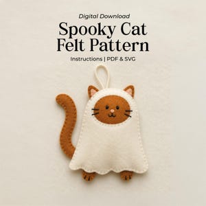 May include: A digital download for a Spooky Cat Felt Pattern including instructions, PDF, and SVG files. The image shows a brown felt cat wearing a white ghost costume with a long tail, small ears, black whiskers, and a hanging loop at the top.