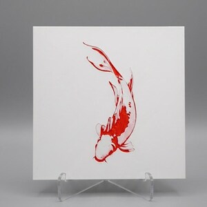 Peut inclure: Une impression carrée blanche présentant une illustration de poisson koï unique réalisée à l'encre rouge vif. Le poisson est représenté dans un mouvement de nage vers le bas avec des écailles détaillées et des nageoires fluides, sur un support en acrylique transparent.