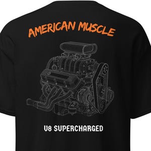 May include: A black short-sleeve t-shirt featuring a white line-art illustration of a supercharged V8 engine on the back. The text AMERICAN MUSCLE appears in orange above the engine, and V8 SUPERCHARGED is printed in white below the graphic.