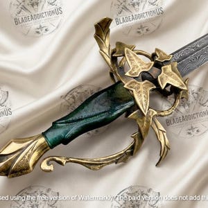 May include: A sword with a patterned Damascus steel blade and a dark green handle. The hilt features an ornate brass guard shaped like ivy leaves and vines, with a matching brass pommel at the base of the grip. The design is intricate and metallic.