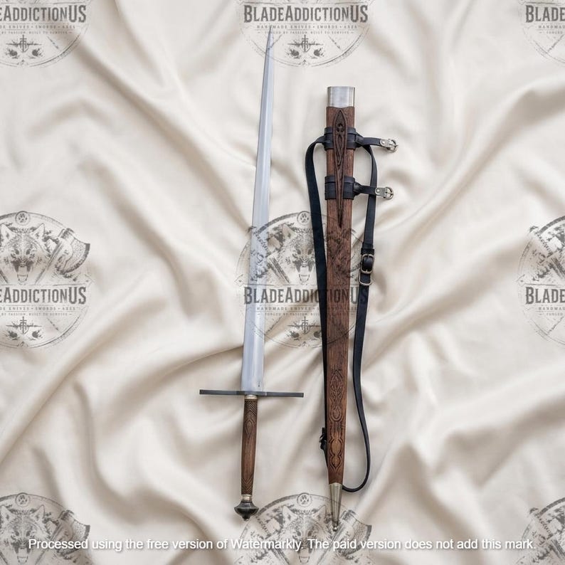 May include: A long, straight-bladed sword with a dark wooden handle and a simple crossguard. Beside it lies a matching wooden scabbard featuring intricate carved patterns, a silver-toned metal tip, and black leather straps with metal buckles.