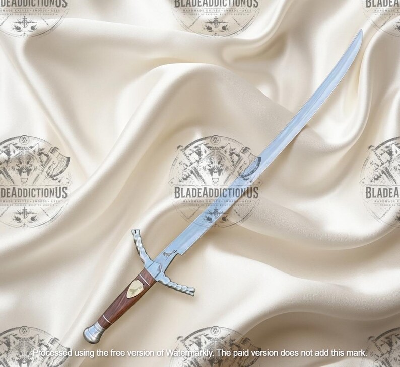 May include: A silver-colored metal sword with a curved blade and a brown wooden handle. The hilt features a metallic crossguard and a pommel, with a small decorative emblem embedded in the center of the grip. The blade is polished and reflective.
