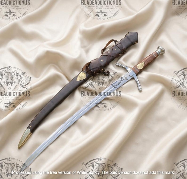 May include: A silver-toned metal sword with a wooden handle and a brass pommel, featuring a crossguard and an engraved blade. Beside the sword lies a dark brown leather scabbard with brass accents, including a pointed tip and a decorative strap.