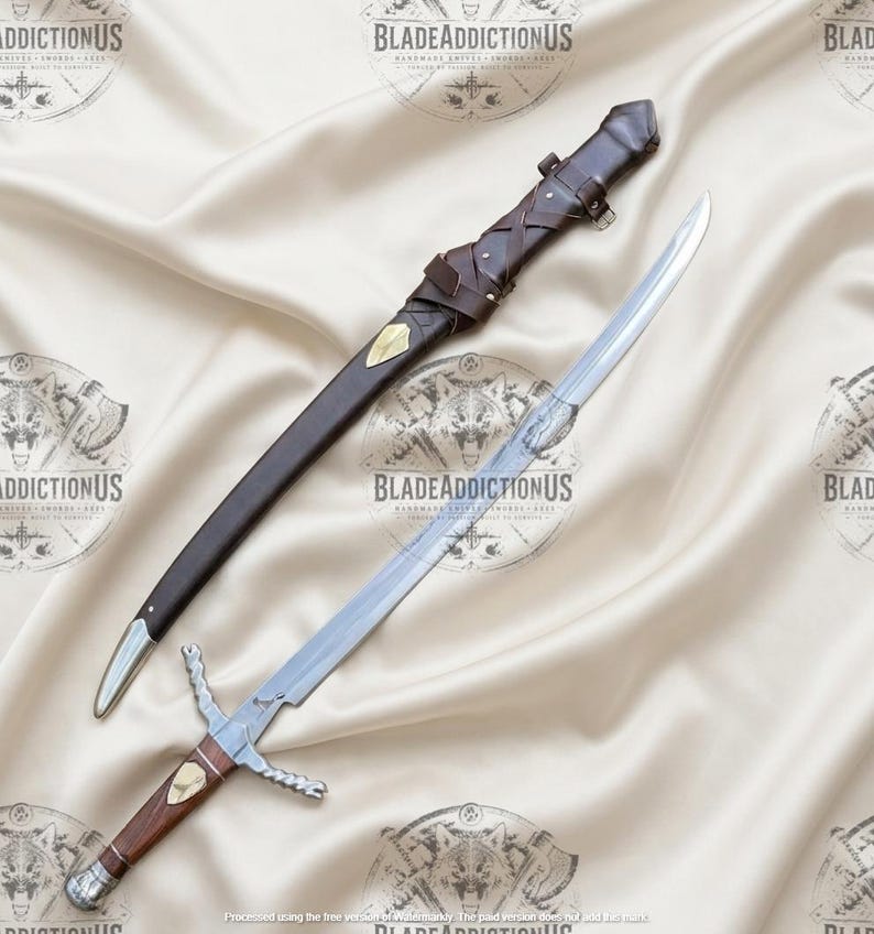 May include: A silver-toned sword with a wooden handle, a metal crossguard, and a matching brown leather scabbard featuring decorative brass accents and leather lacing. The blade is straight and polished, while the scabbard includes a belt loop.