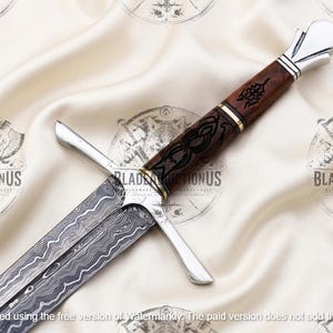 May include: A sword with a patterned Damascus steel blade featuring wavy lines. The hilt has a dark brown wooden handle with black etched designs, a silver-colored crossguard, and a silver-colored pommel. The handle includes gold-colored rings.