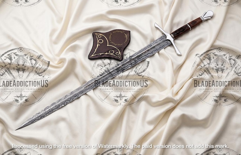 May include: A long sword with a patterned Damascus steel blade, a silver crossguard, and a dark brown wooden handle with silver accents. A small, dark brown, shield-shaped leather sheath with gold-colored decorative line work is placed nearby.