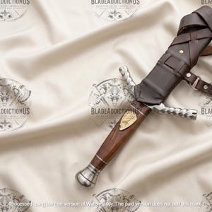 May include: A dagger with a dark wood handle, a silver-toned pommel, and a twisted silver-toned crossguard. The blade is partially encased in a dark brown leather sheath featuring a strap system with metal rivets and a small gold-toned inlay.