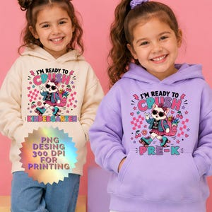 Puede incluir: Una sudadera con capucha color crema y una sudadera color lavanda, ambas con el gráfico de un gato con gafas de sol, chaqueta vaquera y patines. El texto dice I'M READY TO CRUSH KINDERGARTEN y I'M READY TO CRUSH PRE-K con cerezas y estrellas.
