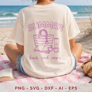 May include: An off-white short-sleeve t-shirt featuring a purple graphic on the back. The design includes the text "SUMMER" and "beach read season" surrounding an illustration of a beach bag, an open book, sunglasses, and a tube of sunscreen.