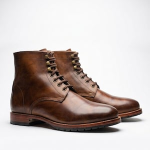 May include: A pair of ankle-high boots crafted from polished brown leather. These boots feature a rounded toe, a stacked wooden heel, and a lace-up front closure with brass-toned metal eyelets and hooks, secured by matching brown laces.