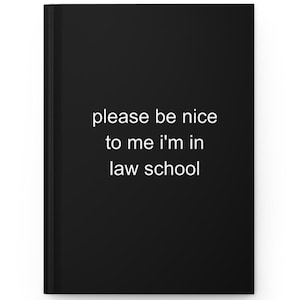 May include: A black hardcover journal featuring the white text please be nice to me i'm in law school centered on the front cover. The notebook has a clean, solid black background with a simple, sans-serif font for the printed message.