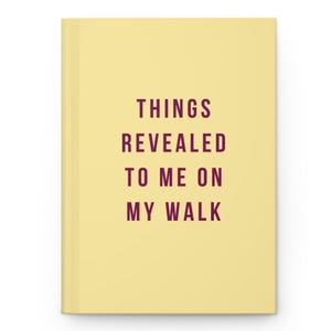 Pode incluir: Um caderno de capa dura amarelo-pálido com o texto em roxo escuro "THINGS REVEALED TO ME ON MY WALK" centralizado na capa. O diário possui um fundo liso e limpo, com uma fonte sem serifa simples e em negrito para o título.