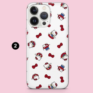 May include: A white smartphone case featuring a repeating pattern of Hello Kitty characters wearing blue outfits and red bows, interspersed with small red bows. The design is printed on a clear case, showing the phone's camera module at the top.