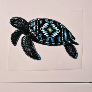 May include: A sticker featuring a sea turtle with a black head and flippers. The turtle shell displays a vibrant geometric pattern in shades of blue, white, and green, with intricate detailing on the skin and shell edges against a white background.