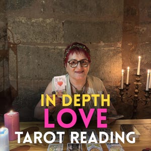 May include: A person with short red hair and glasses holds a tarot card featuring a heart illustration. The text IN DEPTH LOVE TAROT READING is overlaid on the image. Several tarot cards are spread on a wooden table with lit candles nearby.
