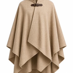 May include: A beige cape with a high collar and a dark brown leather buckle closure at the neck. The garment features a draped, asymmetrical hemline and a soft, felted texture, providing a structured yet flowing silhouette for layering.