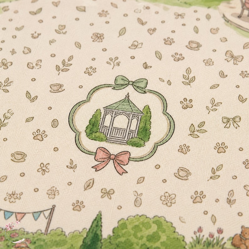 May include: A cream-colored fabric featuring a repeating pattern of small green leaves, bows, paw prints, and teacups. A central scalloped frame with a green bow at the top and a pink bow at the bottom encloses a green gazebo surrounded by bushes.