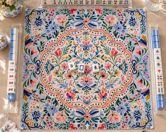 Può includere: Un tappetino da Mahjong quadrato con un motivo floreale simmetrico nei toni del rosa, blu e verde, circondato da quattro supporti in acrilico trasparente contenenti tessere da Mahjong bianche con caratteri e simboli rossi, blu e neri.