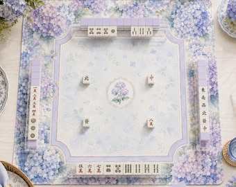 May include: A square mahjong mat featuring a light blue and purple hydrangea floral pattern with a central hydrangea illustration. The mat includes four racks holding white mahjong tiles with various Chinese characters and symbols.