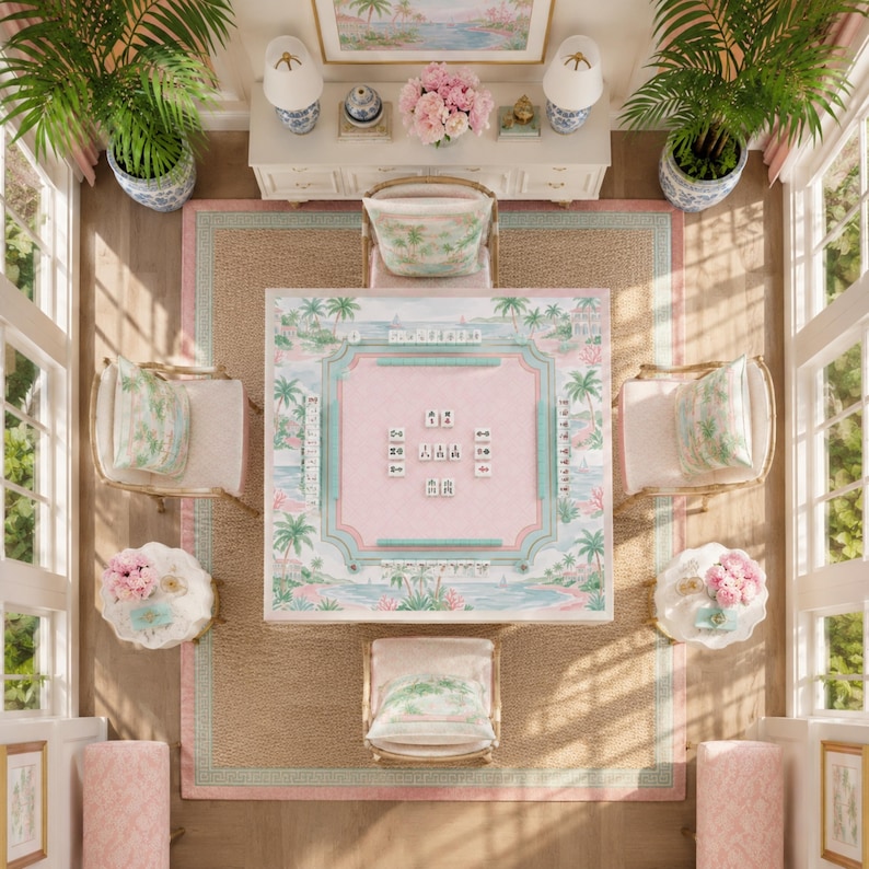 May include: A square mahjong table featuring a pastel pink and green tropical palm tree print, surrounded by four upholstered chairs with matching cushions, set on a large woven area rug in a room with two potted palm plants and side tables.