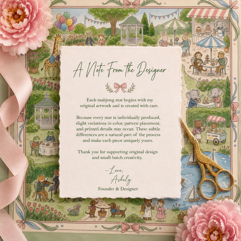 May include: A rectangular card with deckled edges featuring the text A Note From The Designer, placed over a colorful illustration of animals in a park. A gold-colored bird-shaped pair of scissors and pink flowers are positioned on the card.