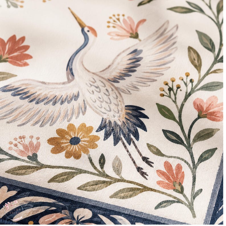 Puede incluir: Una tela de color crema con una ilustraci&oacute;n impresa de una grulla en vuelo con alas azules y blancas. El dise&ntilde;o incluye elementos florales en tonos naranja, rosa y verde, enmarcados por un borde decorativo de color azul oscuro.