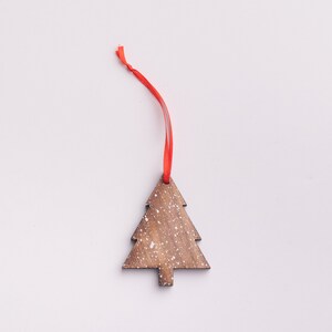 May include: A wooden Christmas tree ornament with a white snowflake design and a red ribbon.