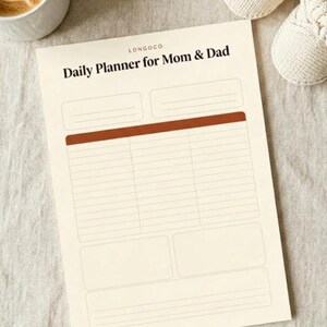 以下が含まれることがあります： 「LONGOCO Daily Planner for Mom & Dad」という黒い文字が印刷されたクリーム色のデイリープランナーシート。上部に2つのボックス、中央に錆色のヘッダーバーが付いた3列の罫線セクション、下部に3つのボックスが配置されたレイアウトです。