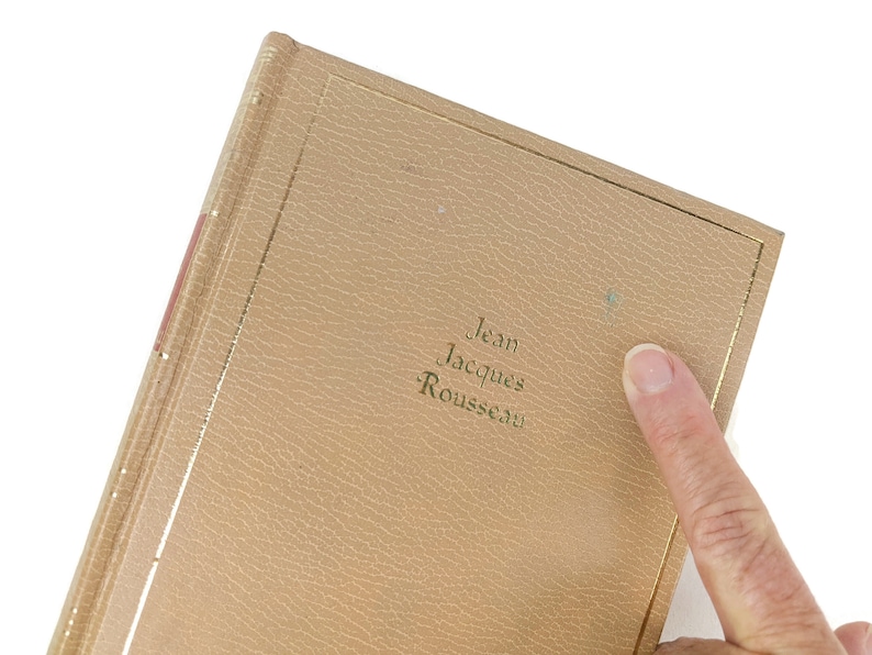 Pode incluir: Um livro encadernado em couro castanho com detalhes dourados e o texto "Jean Jacques Rousseau" na capa.