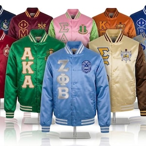 May include: A collection of ten satin varsity jackets in various colours, each featuring distinct Greek letter embroidery and crest patches on the chest. The jackets have ribbed collars, cuffs, and waistbands, with snap-button closures down the front.