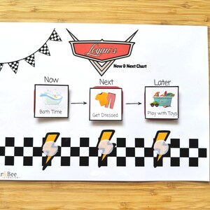 May include: A white rectangular Now & Next chart featuring a red race car emblem with the text Logan's Now & Next Chart. It includes three square icons labelled Bath Time, Get Dressed, and Play with Toys, with a black and white checkered border.