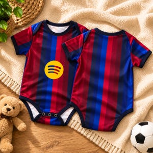 May include: Two short-sleeved baby bodysuits featuring vertical stripes in dark red, navy blue, and bright blue. One bodysuit displays a yellow circular Spotify logo on the chest. Both garments have dark blue trim at the neck and sleeves.