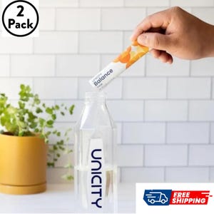 May include: A 2-pack of Unicity Balance orange flavored supplement stick packets and a clear plastic water bottle with the Unicity logo printed in dark blue. The stick packet features a white background with orange circular graphic patterns.